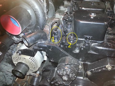 1994 Ford Bronco - A close-up view of an engine compartment shows two yellow circles highlighting specific bolts labeled 1 and 2. The engine features a Holset…