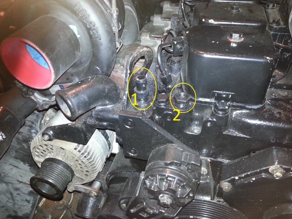 Engine compartment with Holset turbocharger and alternator, with two bolts circled and labeled 1 and 2.