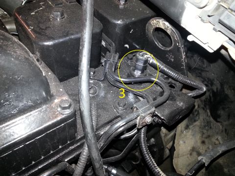1994 Ford Bronco - A close-up view of a black engine component with several fuel lines connected to it. One fuel line connection point is circled in yellow an…