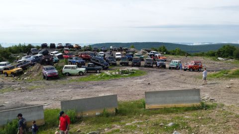 1979 Ford Bronco - A large gathering of off-road vehicles, predominantly Ford Broncos and trucks, are parked on a rocky, elevated terrain with a scenic overlo…