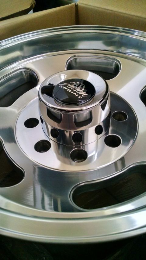1979 Ford Bronco - A close-up, angled shot shows the polished chrome center cap and lug nut area of a custom aftermarket wheel. The center cap has a black bac…