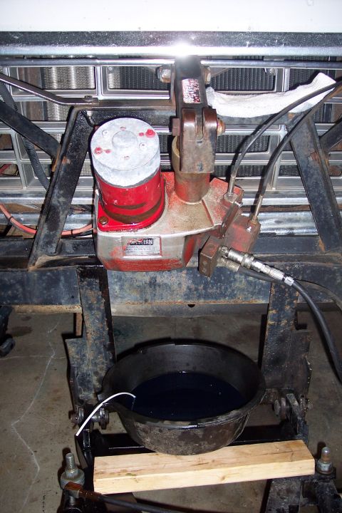 1973 Ford F-250 - A close-up view shows a hydraulic pump assembly mounted on a vehicle frame, with a drain pan filled with dark fluid positioned beneath it.…