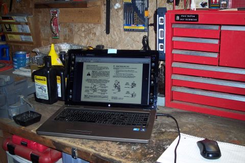 1973 Ford F-250 - A laptop is open on a workbench, displaying a document with diagrams and text related to a pump pressure test. Next to the laptop are bottl…