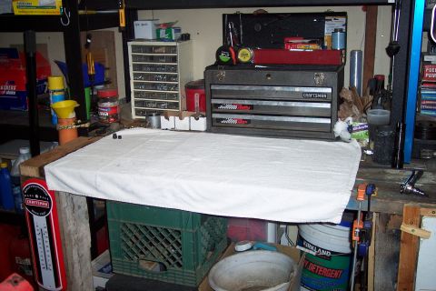 1973 Ford F-250 - A workbench covered with a white towel, with various tools and storage containers in the background. A red and white thermometer is attache…