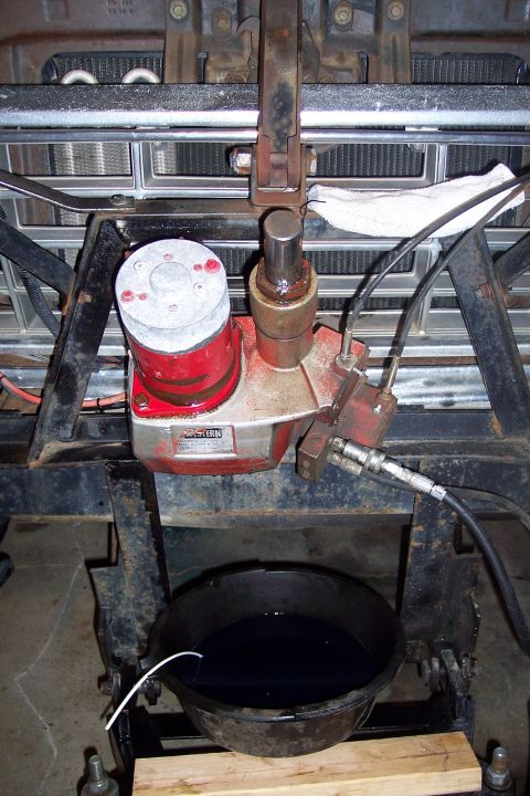 1973 Ford F-250 - A red and silver hydraulic pump is mounted on a black metal frame, with a black oil drain pan positioned below it. The pump has a label tha…