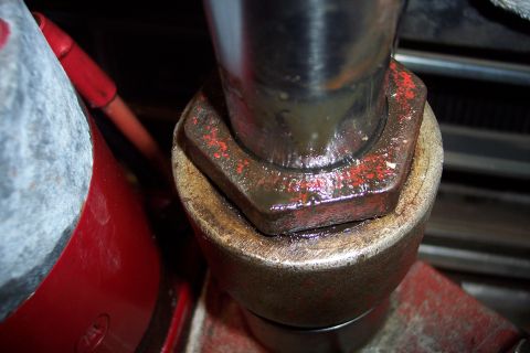 1973 Ford F-250 - A close-up view shows a hexagonal metal part, likely a socket or nut, covered in grease and red paint flecks, engaging with another cylindr…