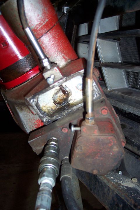 1973 Ford F-250 - A close-up view shows hydraulic lines and fittings attached to a red and silver mechanical component, likely part of a tractor or heavy equ…