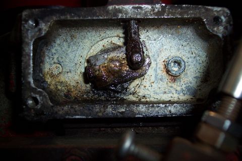 1973 Ford F-250 - A close-up view of a heavily corroded and greasy mechanical linkage inside a metal housing. The linkage appears to be part of a larger asse…