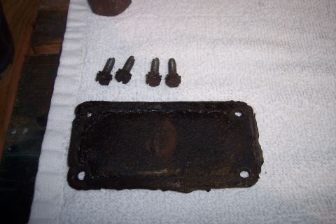 1973 Ford F-250 - A rusty rectangular metal plate with four bolt holes is shown with four matching bolts on a white towel. The plate appears to be a gasket o…