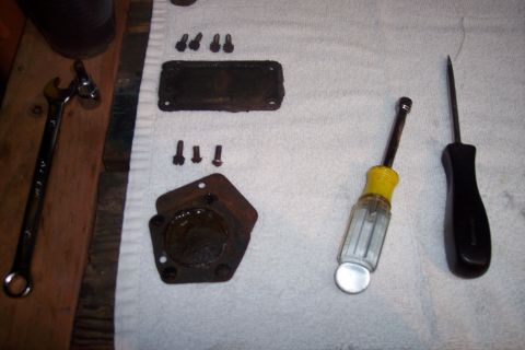 1973 Ford F-250 - A collection of rusty automotive parts and tools are laid out on a white towel. Visible items include a wrench, several bolts, a rectangula…
