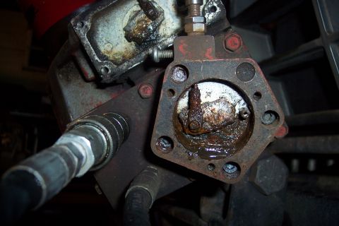 1973 Ford F-250 - A close-up view of a rusty hydraulic pump assembly with a hydraulic hose attached. The internal components are heavily corroded and covered…
