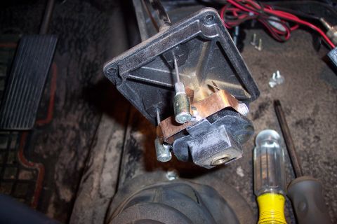 1973 Ford F-250 - A close-up view of a disassembled part of a vehicle's interior, likely related to the pedals or shifter mechanism, with wires and tools vis…