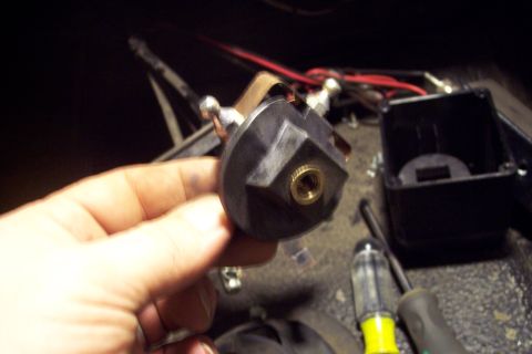 1973 Ford F-250 - A hand holds a black electrical switch with brass terminals and a threaded brass insert. A black plastic electrical box and red wires are v…