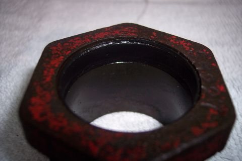 1973 Ford F-250 - A close-up, angled view of a hexagonal metal part with red paint flecks on a white, textured surface. The interior of the part is dark and…