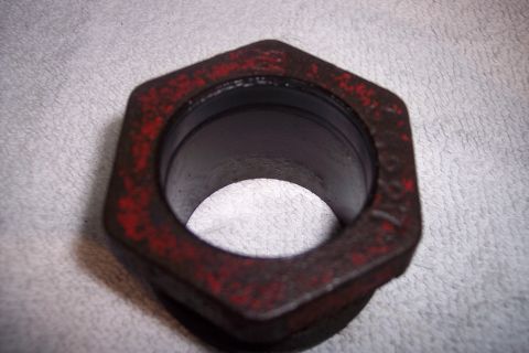 1973 Ford F-250 - A close-up, slightly angled view of a hexagonal metal part with red paint remnants. The part appears to be a bushing or adapter with a holl…