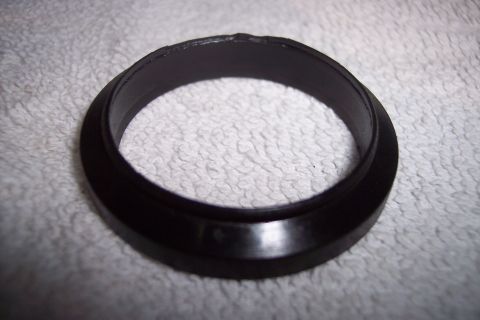 1973 Ford F-250 - A dark-colored ring, possibly a gasket or seal, is shown resting on a textured white surface. The ring has a beveled edge and appears to be…