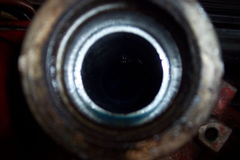 1973 Ford F-250 - A close-up, downward-facing view into a dark, cylindrical opening, possibly a fluid reservoir or intake. A small amount of dark blue fluid…