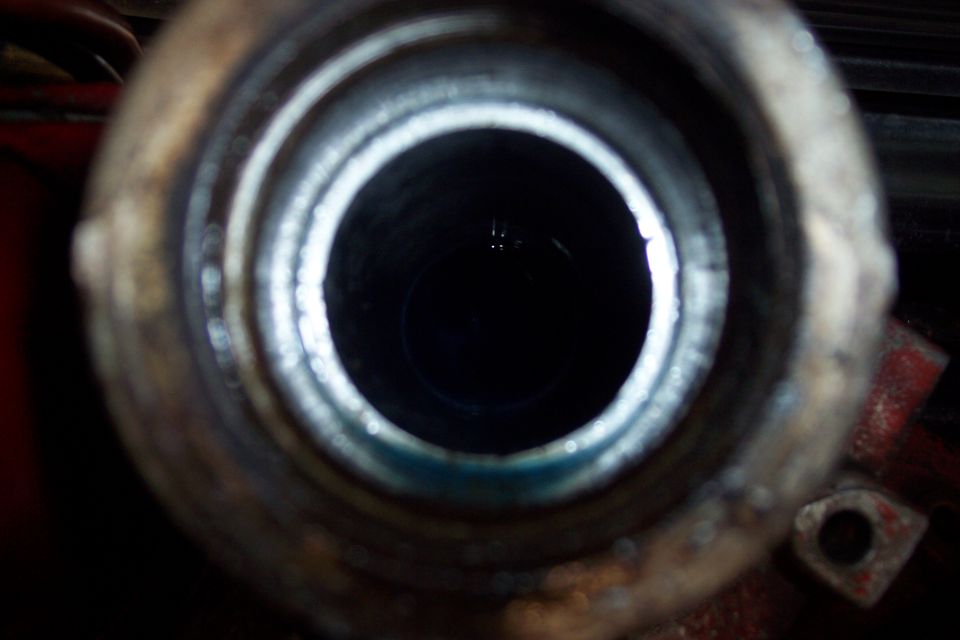 View into a dark, cylindrical opening with blue fluid at the bottom.