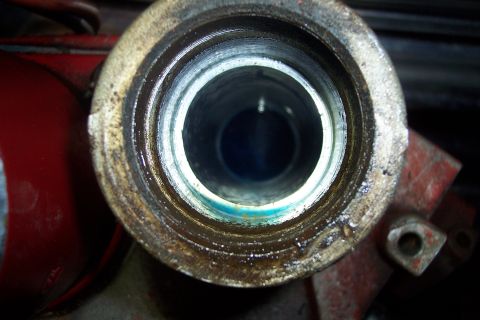 1973 Ford F-250 - A close-up view looks down into a metal pipe fitting, likely part of a hydraulic system, showing wear and grease. The fitting is attached t…