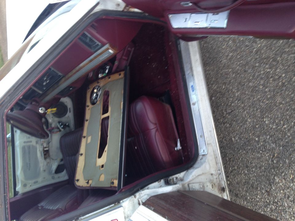 Interior of a classic station wagon with burgundy seats and removed driver's side door panel.