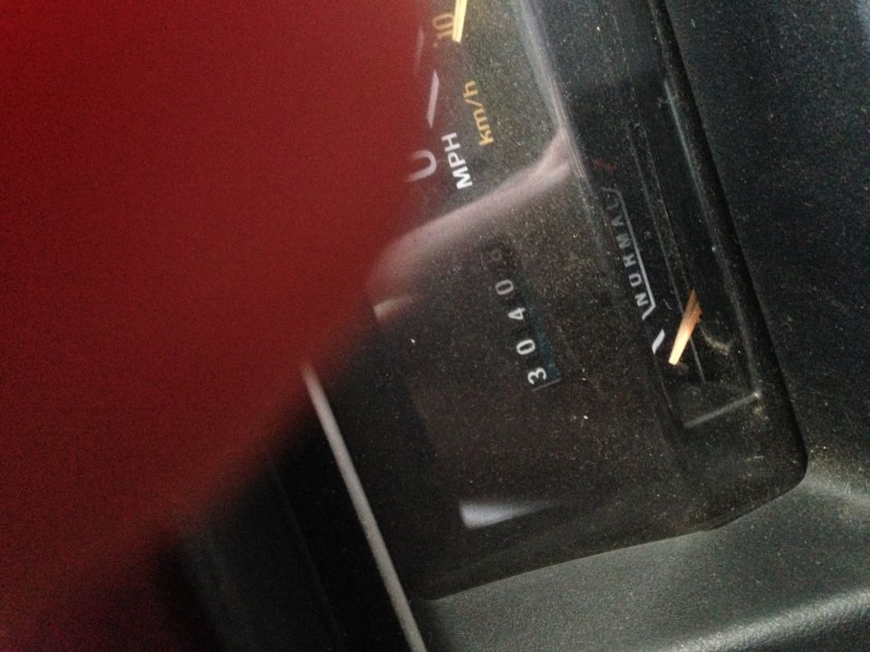 Dusty odometer reading 30408 and fuel gauge on a vehicle dashboard.