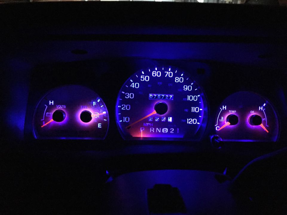Car dashboard with glowing blue gauges at night