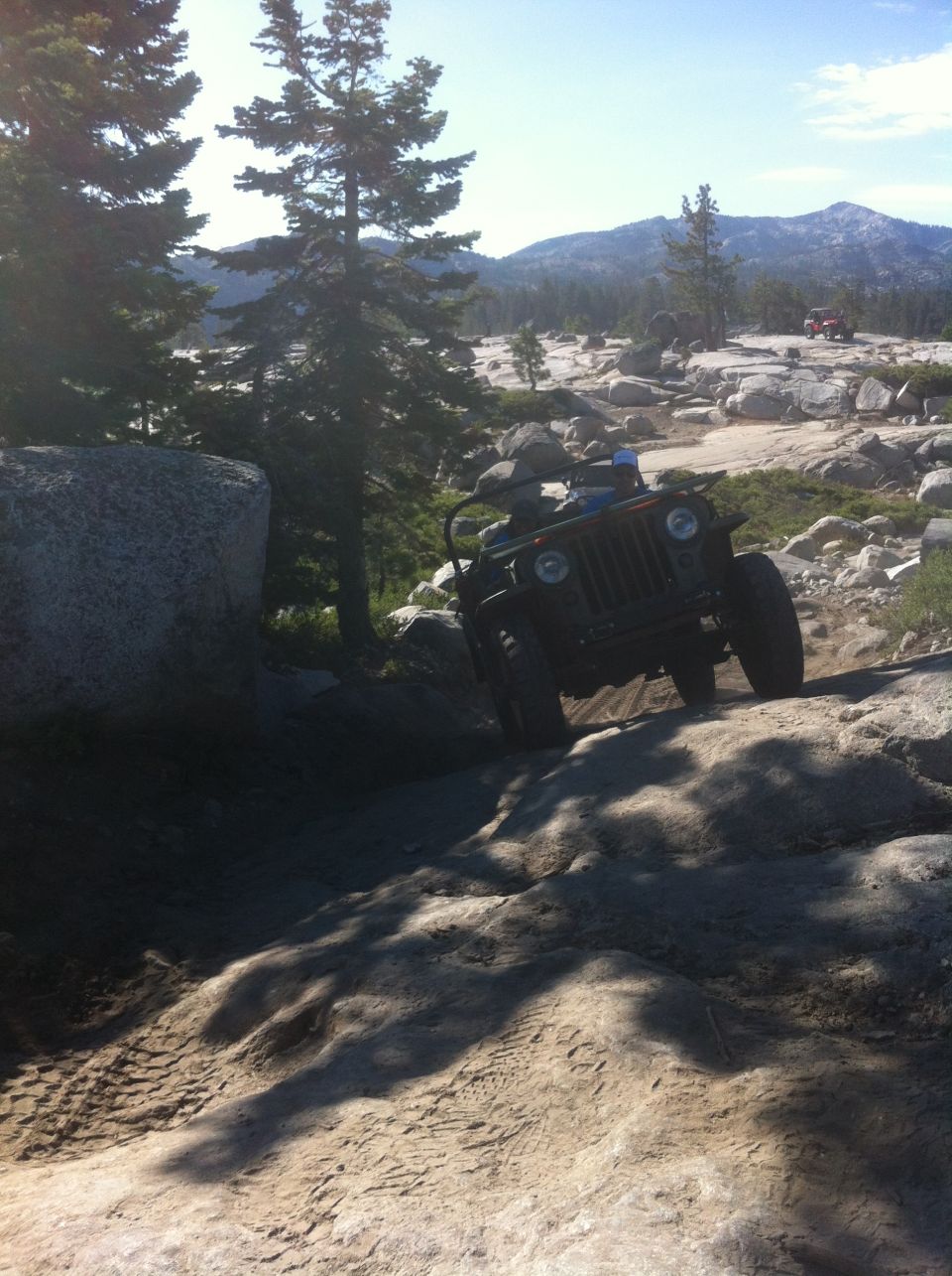 Dark colored Jeep climbing a rocky trail.