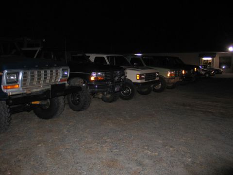 1995 Ford Bronco - Several Ford Broncos and other trucks are parked in a lot at night, with one vehicle in the foreground.