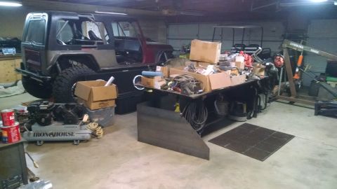 1985 Jeep CJ7 - A partially disassembled Jeep CJ7 is parked in a garage next to a workbench cluttered with tools and boxes. An air compressor and other equ…