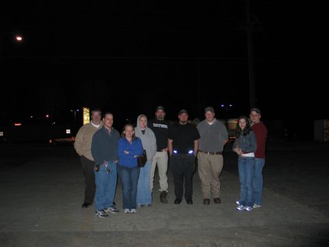 1995 Ford Bronco - A group of people stand together in a dimly lit parking lot at night.