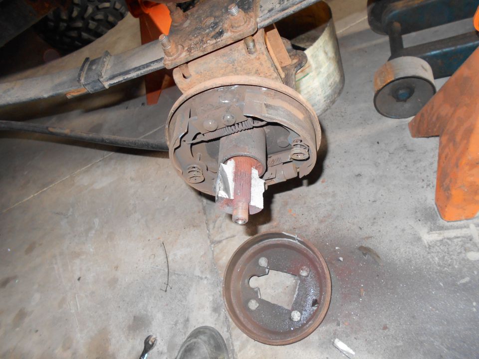 Vehicle drum brake assembly with brake drum removed, showing brake shoes and springs.