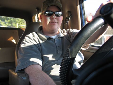 1995 Ford Bronco - Man in sunglasses and cap behind the wheel of a truck.