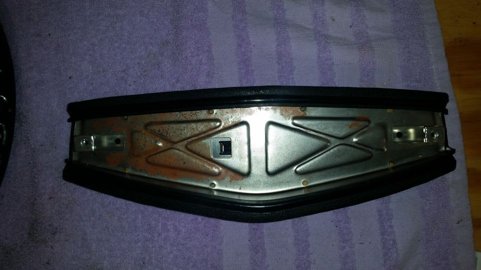 Underside of car part with rust and black rubber seal