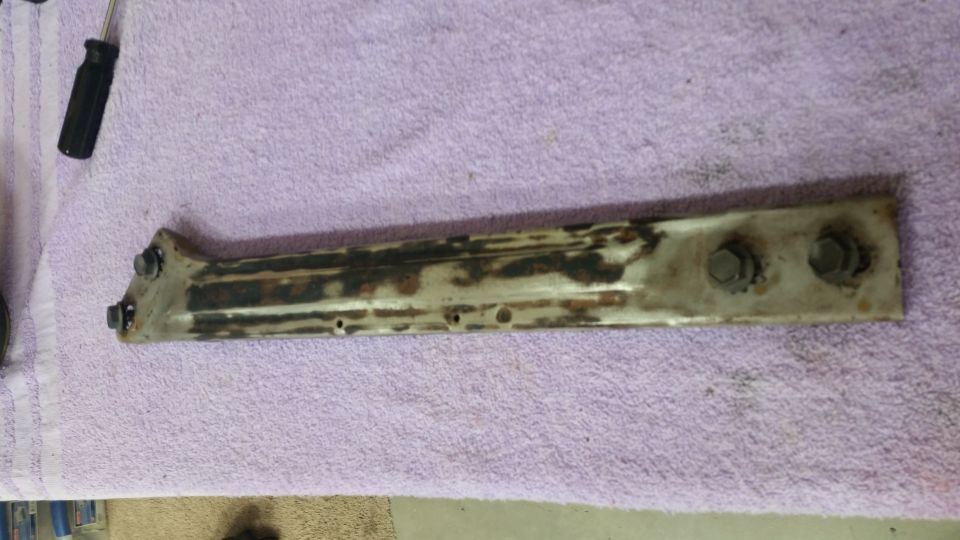 Rusted metal bracket with bolts on a purple towel.