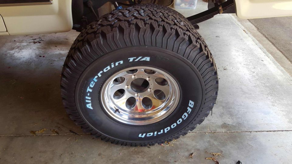 BFGoodrich All-Terrain T/A tire on a chrome rim of a beige vehicle.