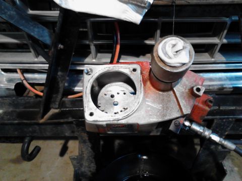 1973 Ford F-250 - A close-up view of a red and silver hydraulic pump assembly, possibly for a snow plow, mounted in front of a vehicle's grille. The pump has…