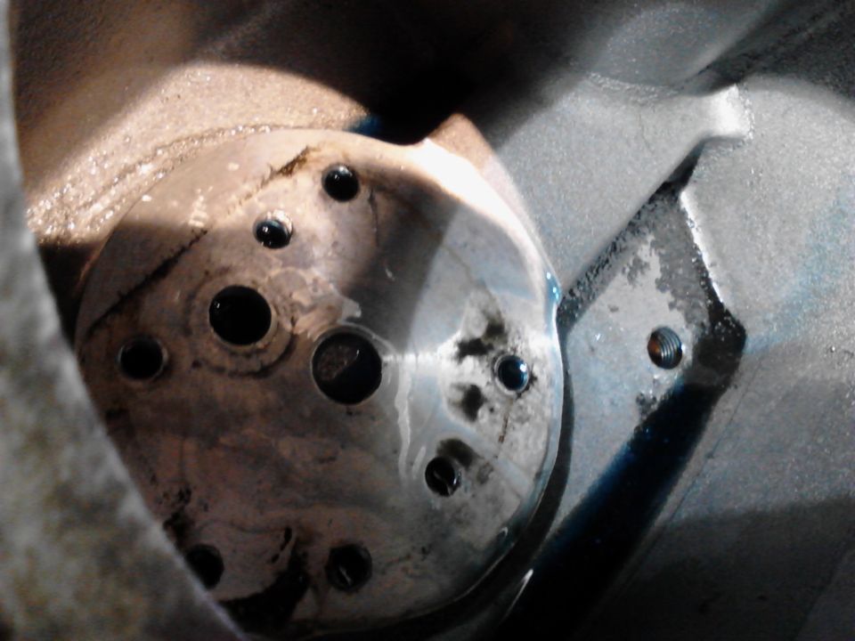 Close-up of a metal part with holes, possibly from a vehicle engine.