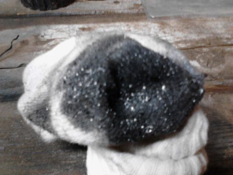 1973 Ford F-250 - A close-up of a dirty, possibly snow-covered, black and white knitted object, possibly a glove or hat, resting on a wooden surface.