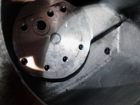 1973 Ford F-250 - Close-up view of a metal component with several drilled holes, some containing dark liquid, possibly oil or coolant. The component appears…