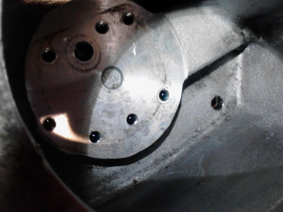 Close-up of a metal plate with drilled holes containing dark liquid.