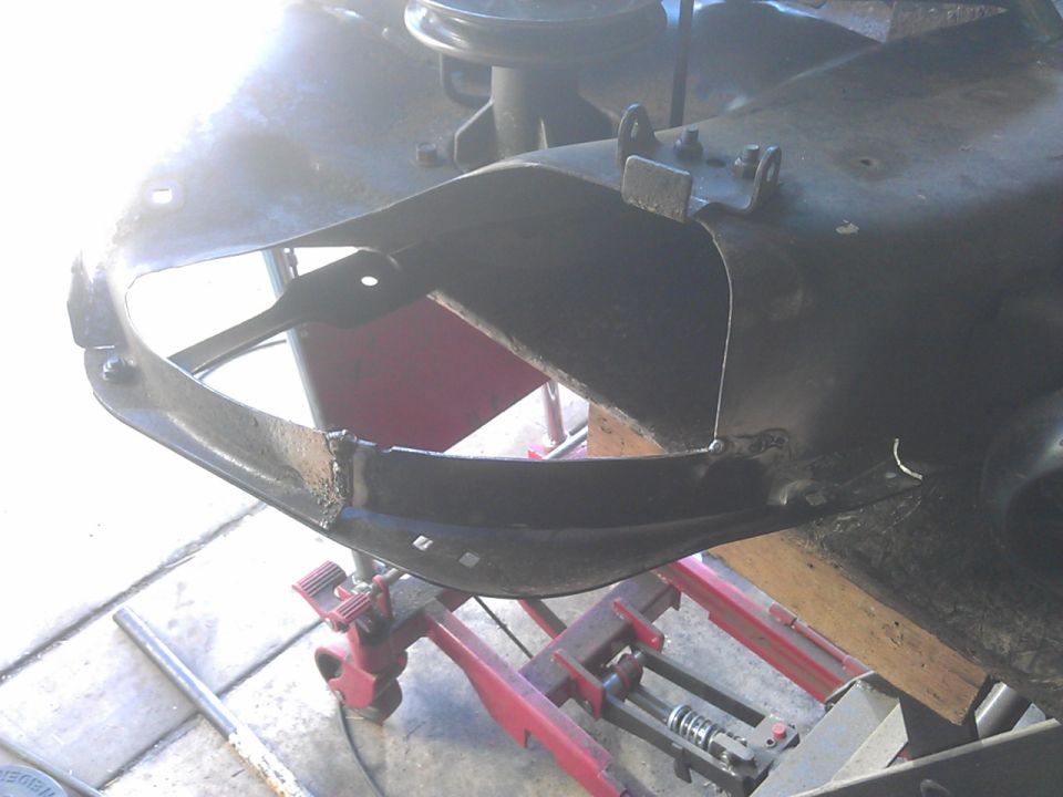 Modified black metal frame on a red hydraulic lift, showing visible welds.