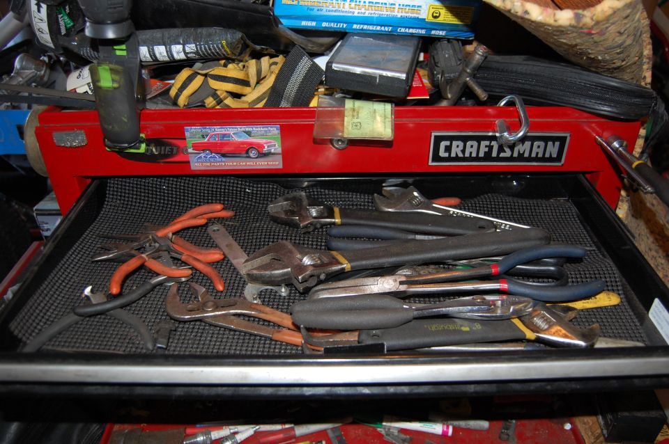 Red Craftsman toolbox drawer filled with pliers and wrenches, sticker of a red classic car.