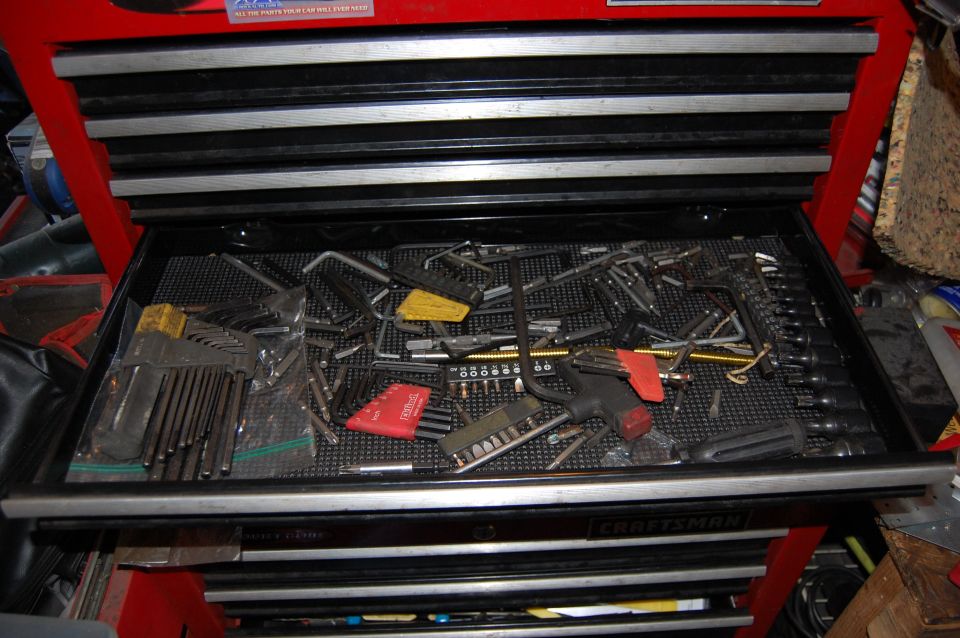 Open red and black tool chest drawer filled with hex keys and screwdriver bits.