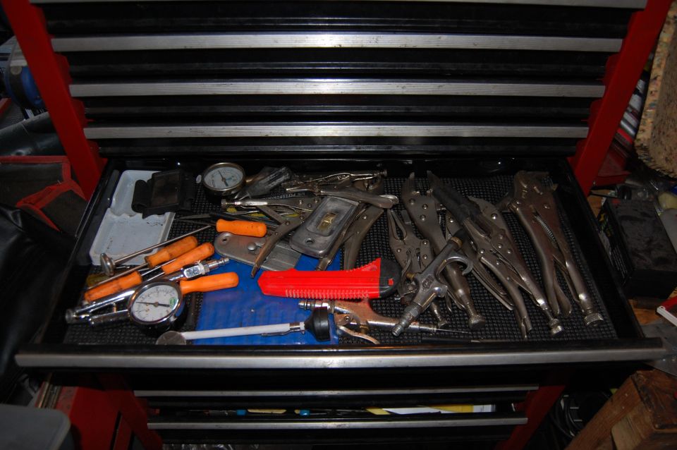Open toolbox drawer with pliers, gauges, and a utility knife.