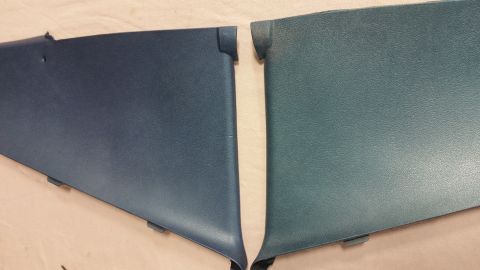 2015 Chevrolet new - Two dark teal and navy blue plastic trim pieces are laid out side-by-side on a light-colored surface. The pieces have a textured finish and…