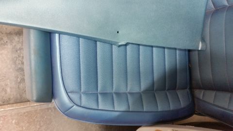 2015 Chevrolet new - A close-up view of the quilted blue upholstery of a vehicle seat, with a light blue plastic panel resting on top.
