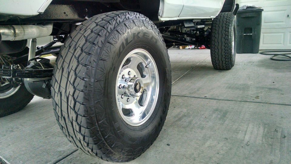 Close-up of a large off-road tire and chrome wheel on a lifted vehicle.