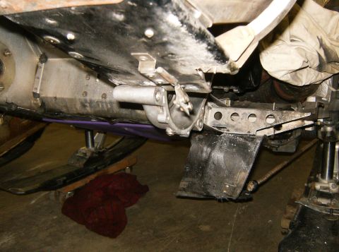 2000 Ford E350 - The underside of a snowmobile is shown, with its skis resting on a wooden dolly and a red cloth underneath. A metal bracket and part of the…