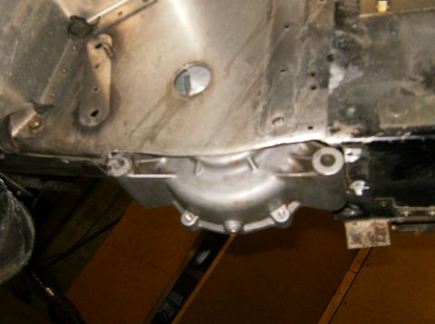 2000 Ford E350 - The underside of a vehicle shows a silver-colored transmission housing bolted to the chassis. The housing has several bolts and mounting po…