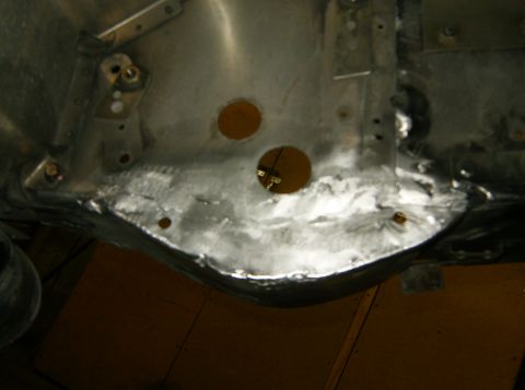 2000 Ford E350 - The underside of a vehicle's chassis shows metalwork with two circular cutouts and evidence of welding. Various brackets and bolts are visi…